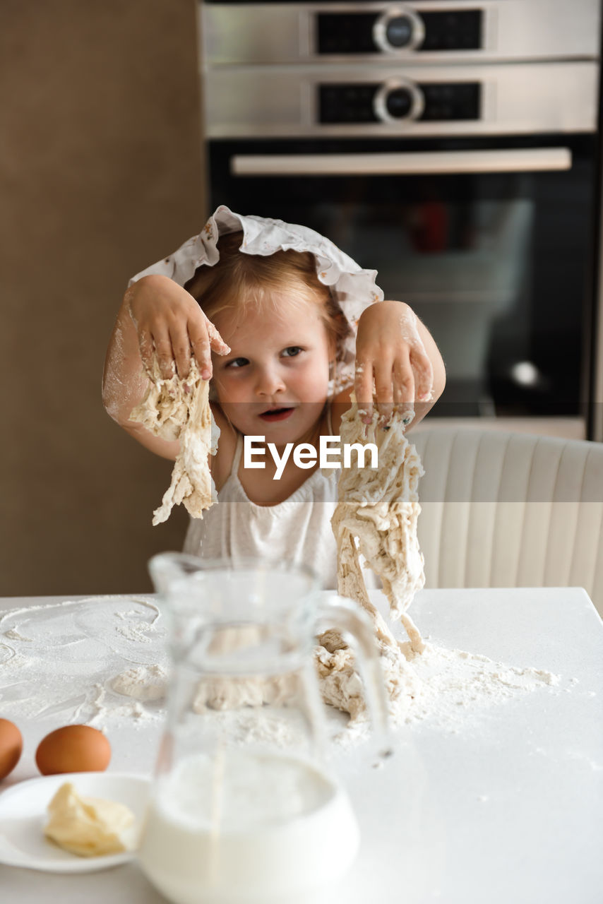 Little girl cooking pizza in the kitchen