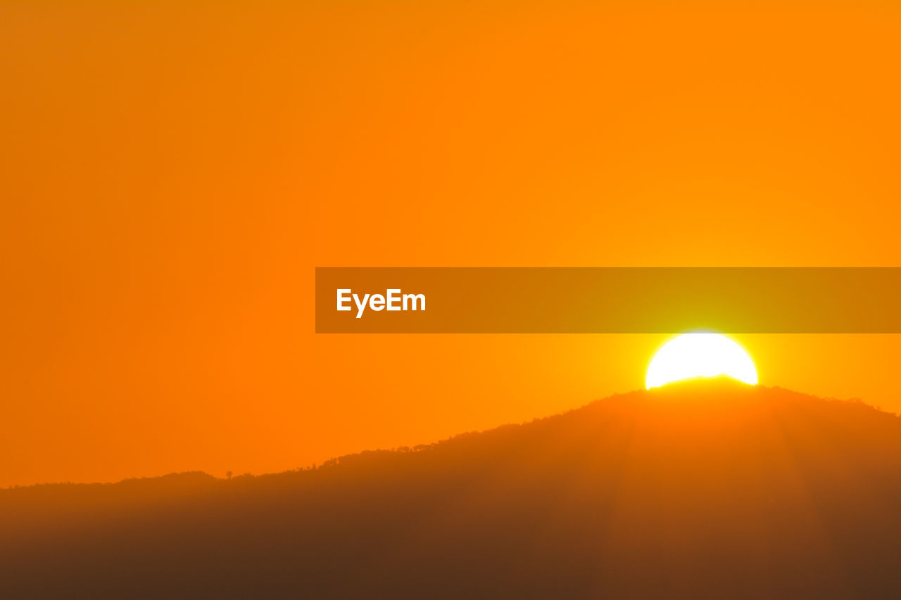 Scenic view of sunset over hill