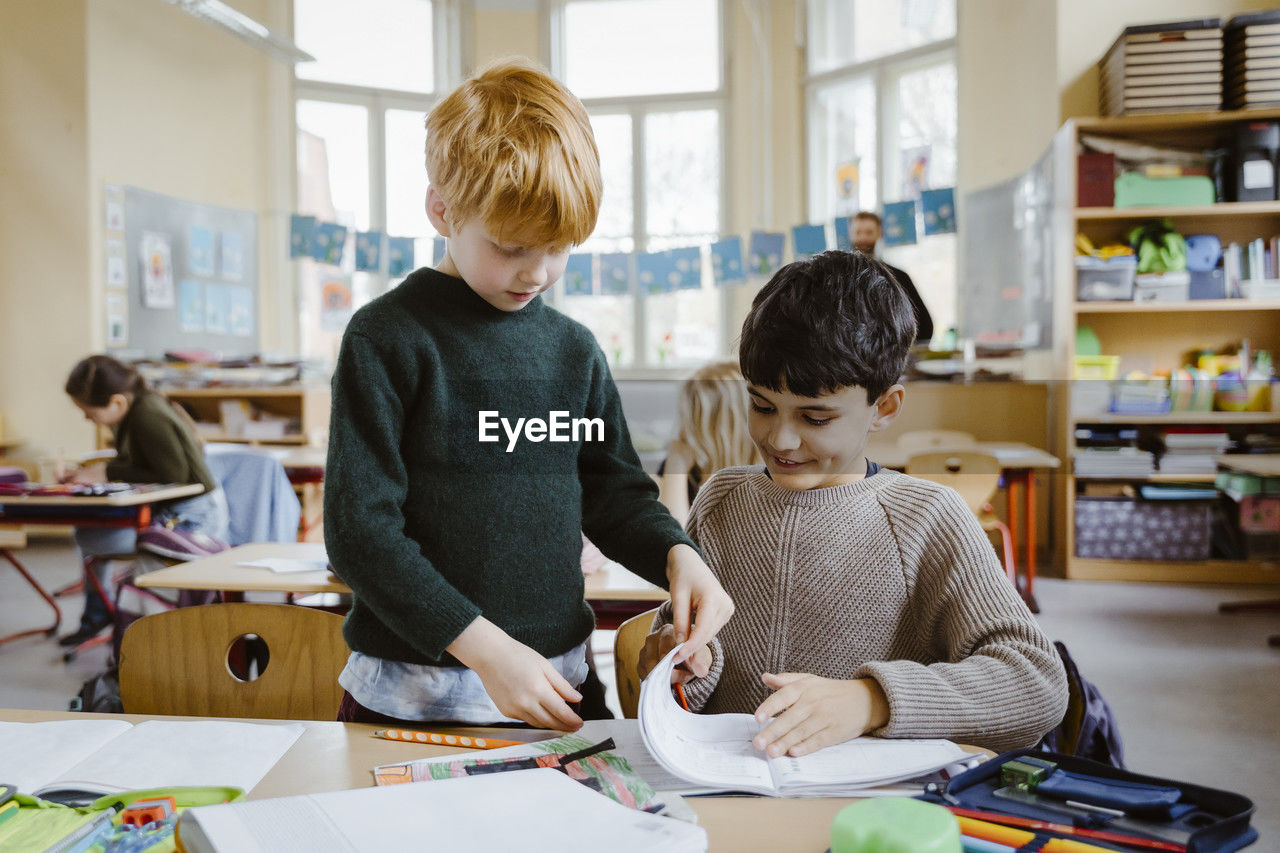 Boys sharing book while learning in classroom