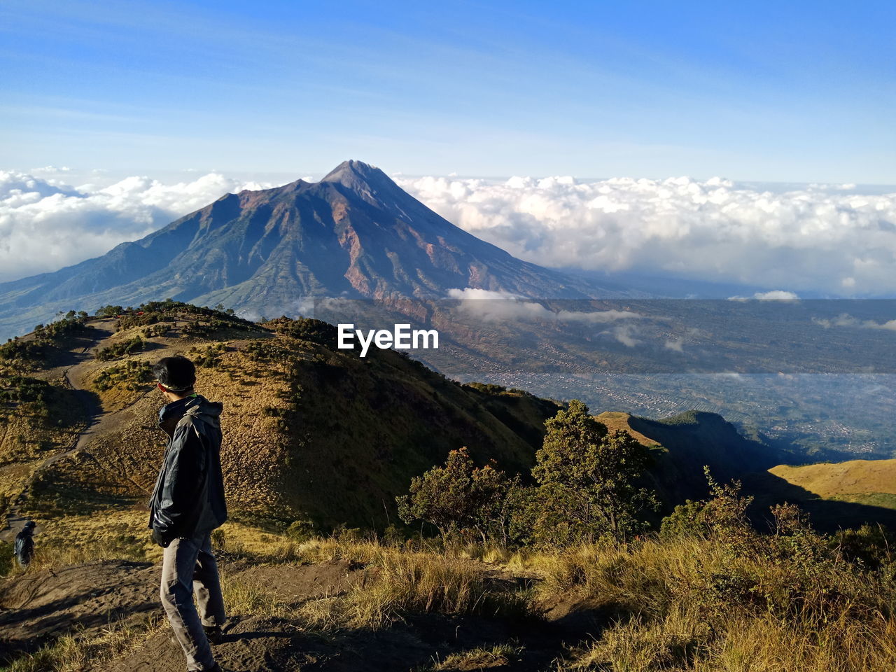 A man looks at mount merapi from mount merbabu