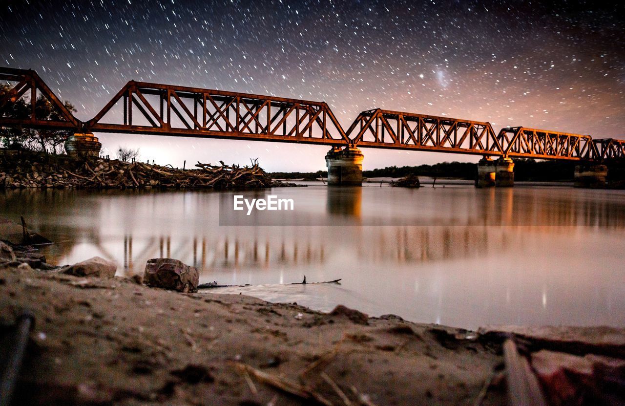 Bridge over river against sky at night