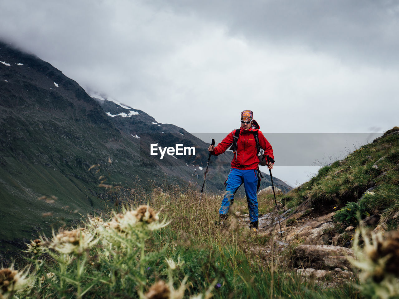 REAR VIEW OF MAN STANDING ON MOUNTAIN PEAK