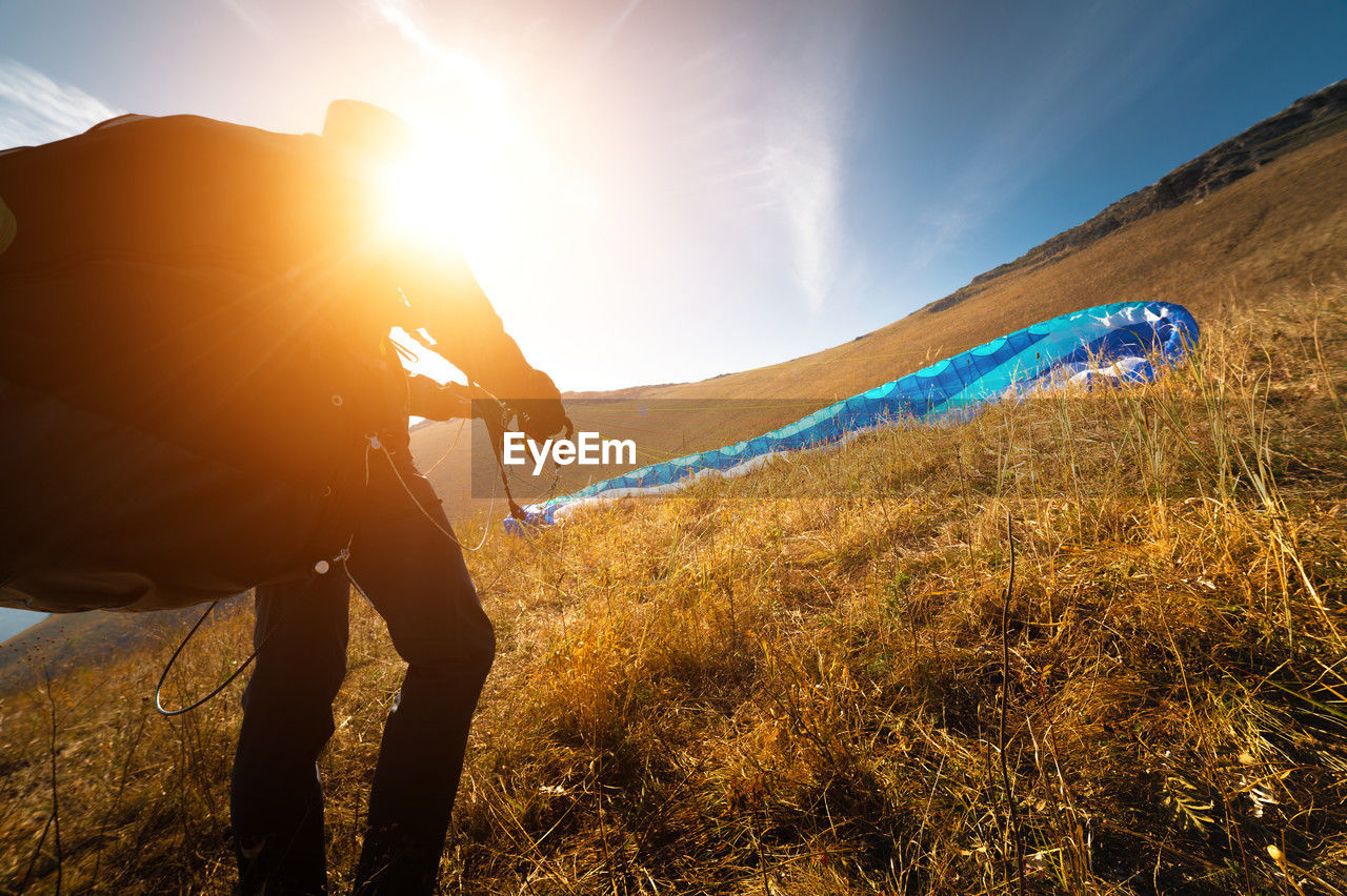 The paraglider is preparing to take off. a colorful kite lies on the grass, in the background there