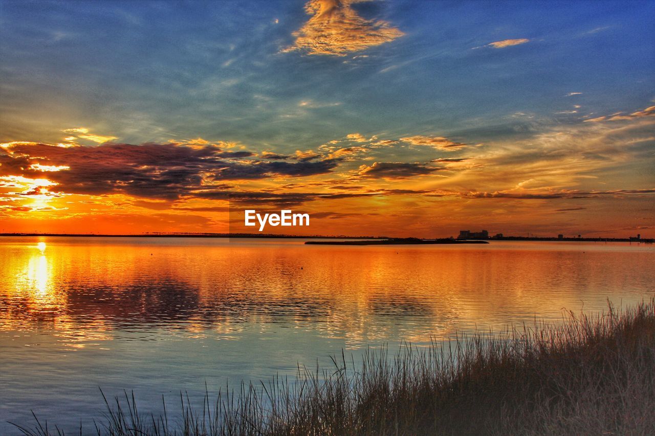 SCENIC VIEW OF LAKE AGAINST SKY AT SUNSET