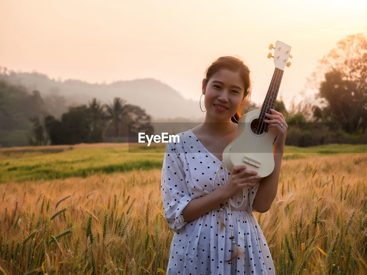 portrait of young woman standing on field against sky