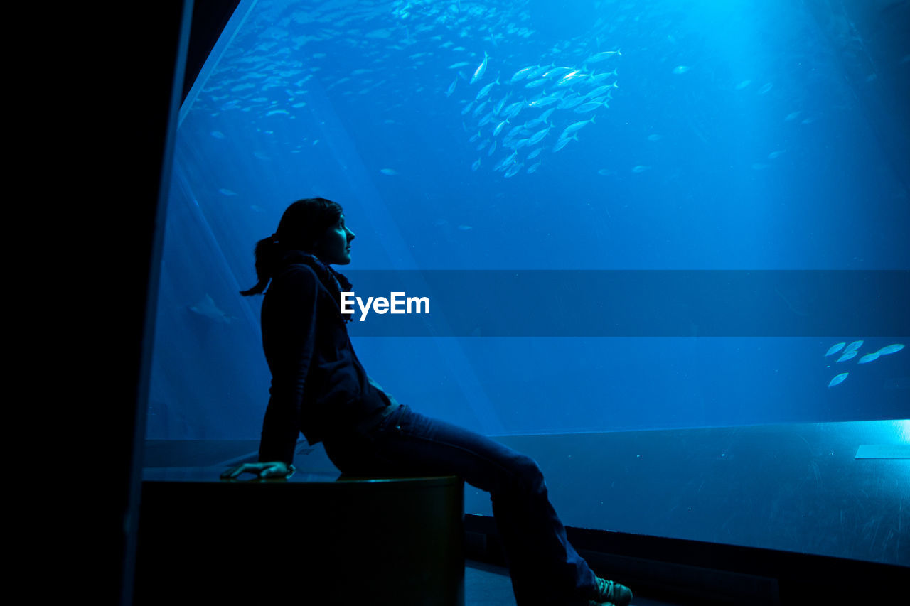 Woman sitting in aquarium 