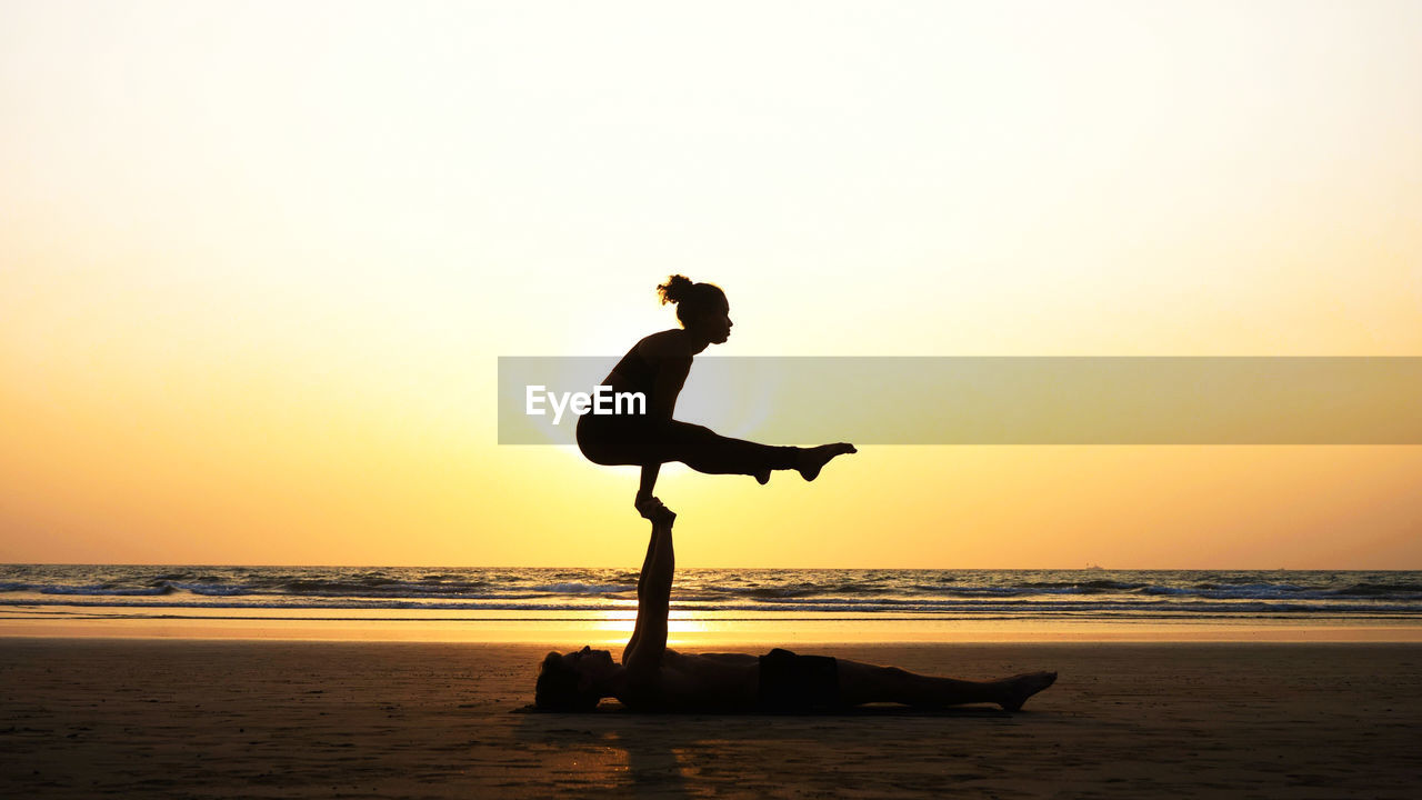 Man and woman doing yoga at beach