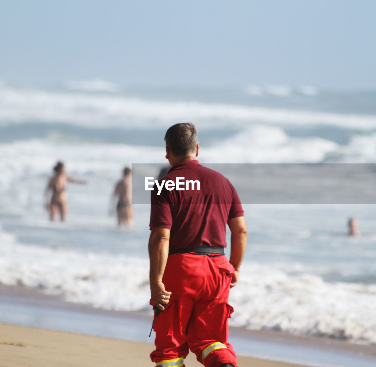 Rear view of man standing at beach against sky