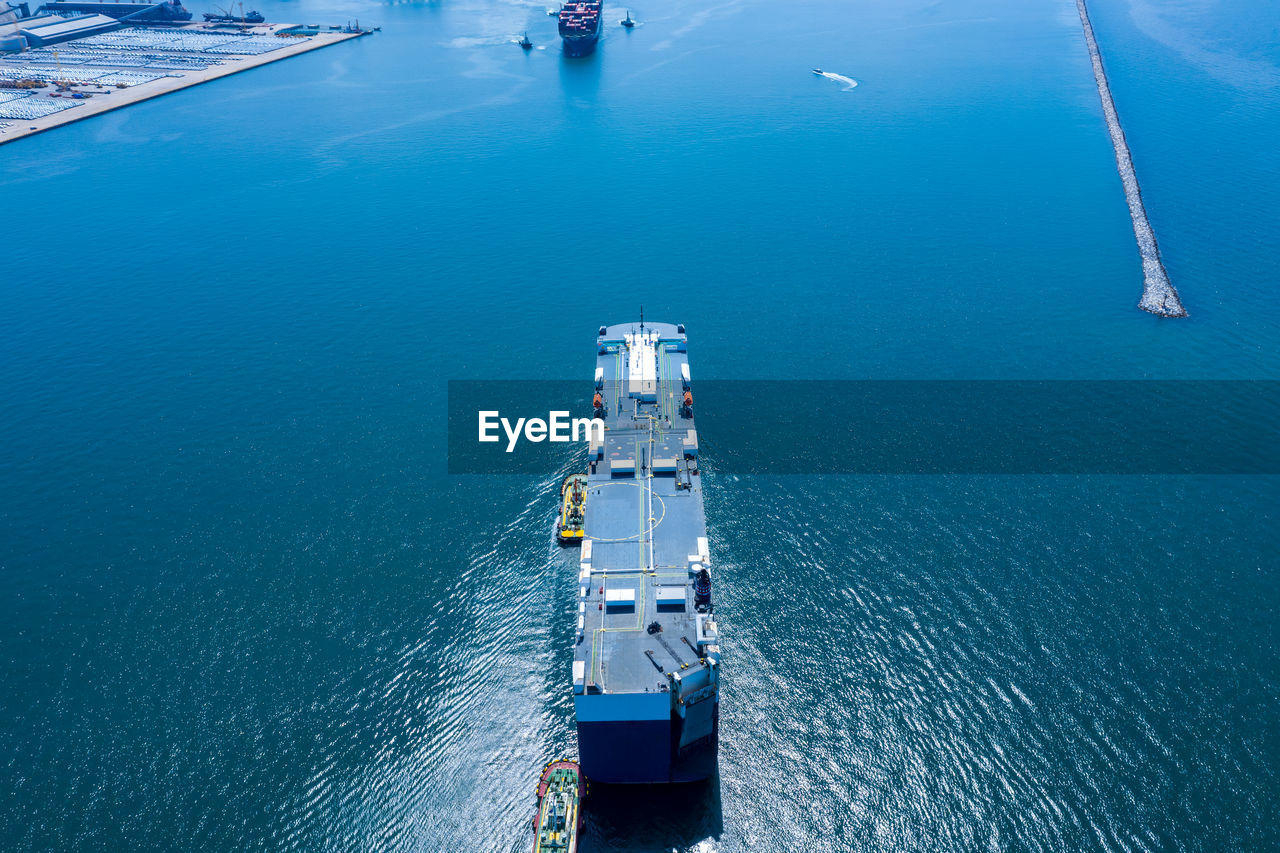 Aerial view ro-ro ship loading new cars. automotive container carriers sailing on the sea export 