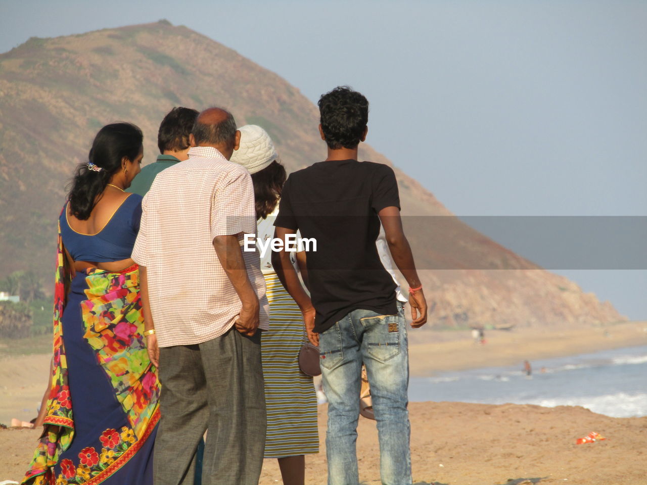 REAR VIEW OF COUPLE STANDING ON MOUNTAIN