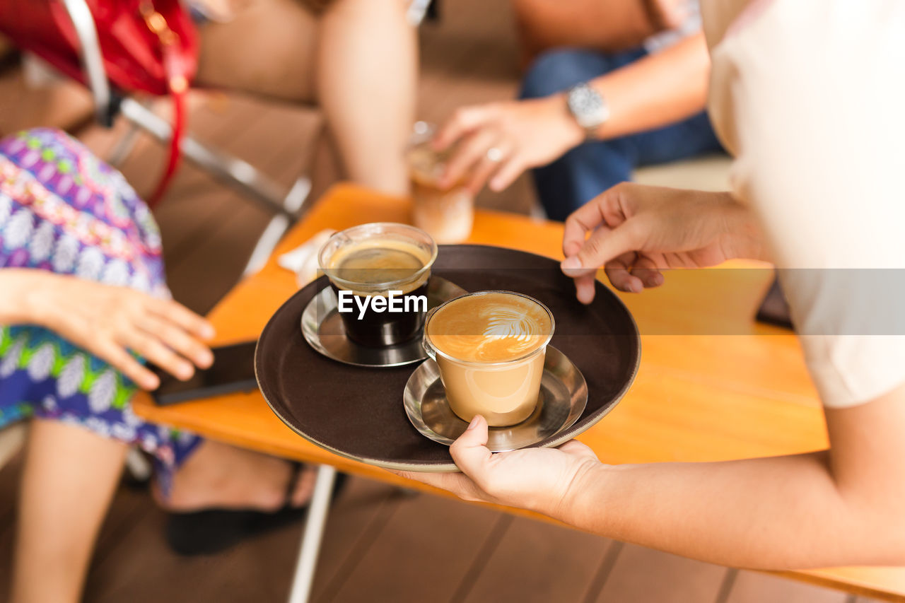 Waitress serving customer a hot coffee at cafe.