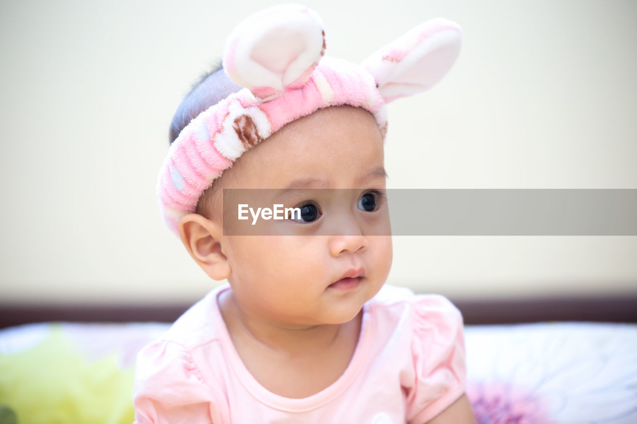 Cute baby girl wearing bunny ears headband at home