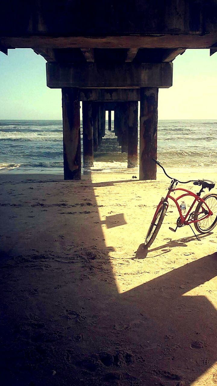 Bicycle parked at beach under pier