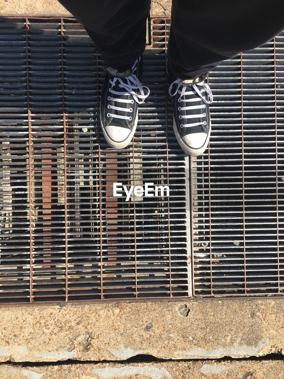 Low section of person standing on metal grate