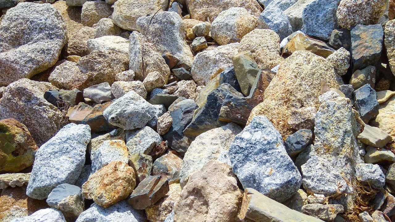 rock, full frame, backgrounds, day, boulder, high angle view, no people, nature, land, beach, rubble, stone, sunlight, large group of objects, abundance, textured, geology, stone wall, gravel, outdoors, bedrock, pattern, rough, tranquility, pebble