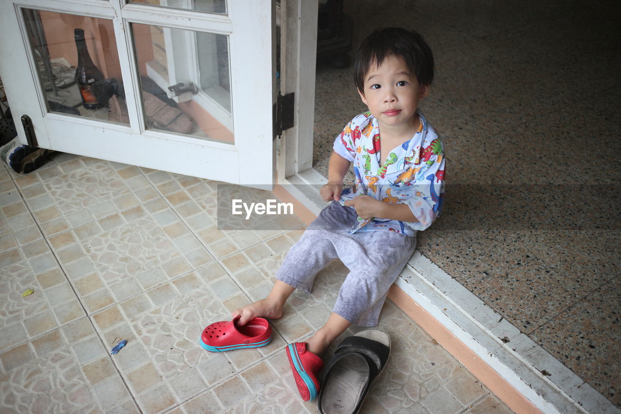 Portrait of young boy sitting in doorway