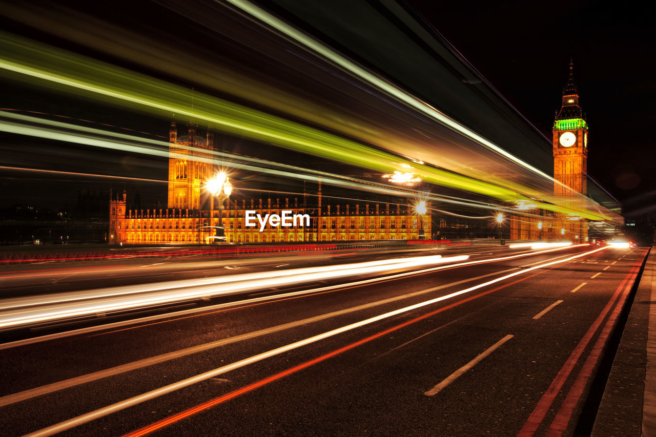 Light trails on road by big ben at night