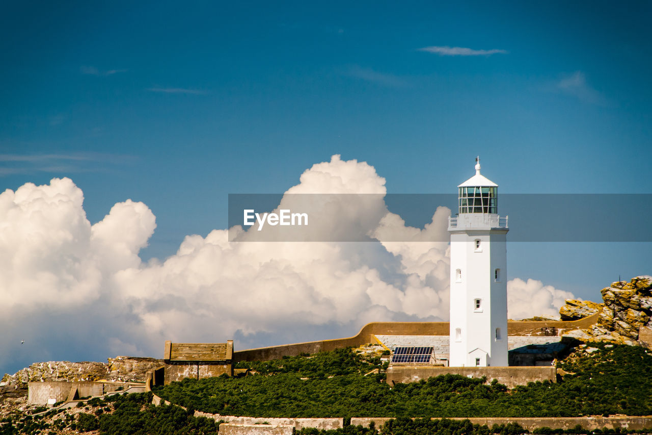 Lighthouse on rock formation against sky