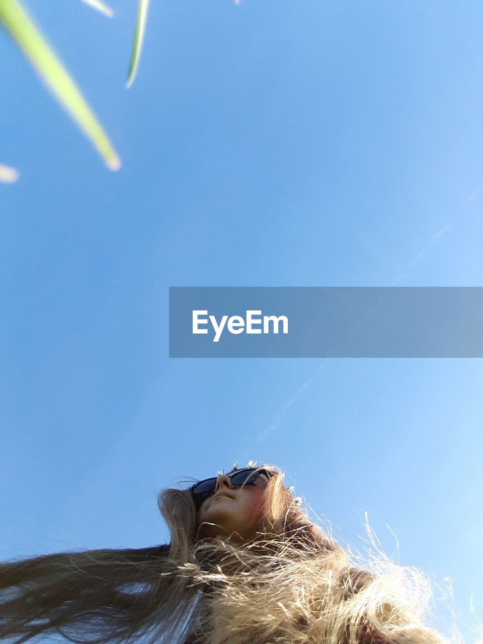 Low angle view of young woman standing against clear sky