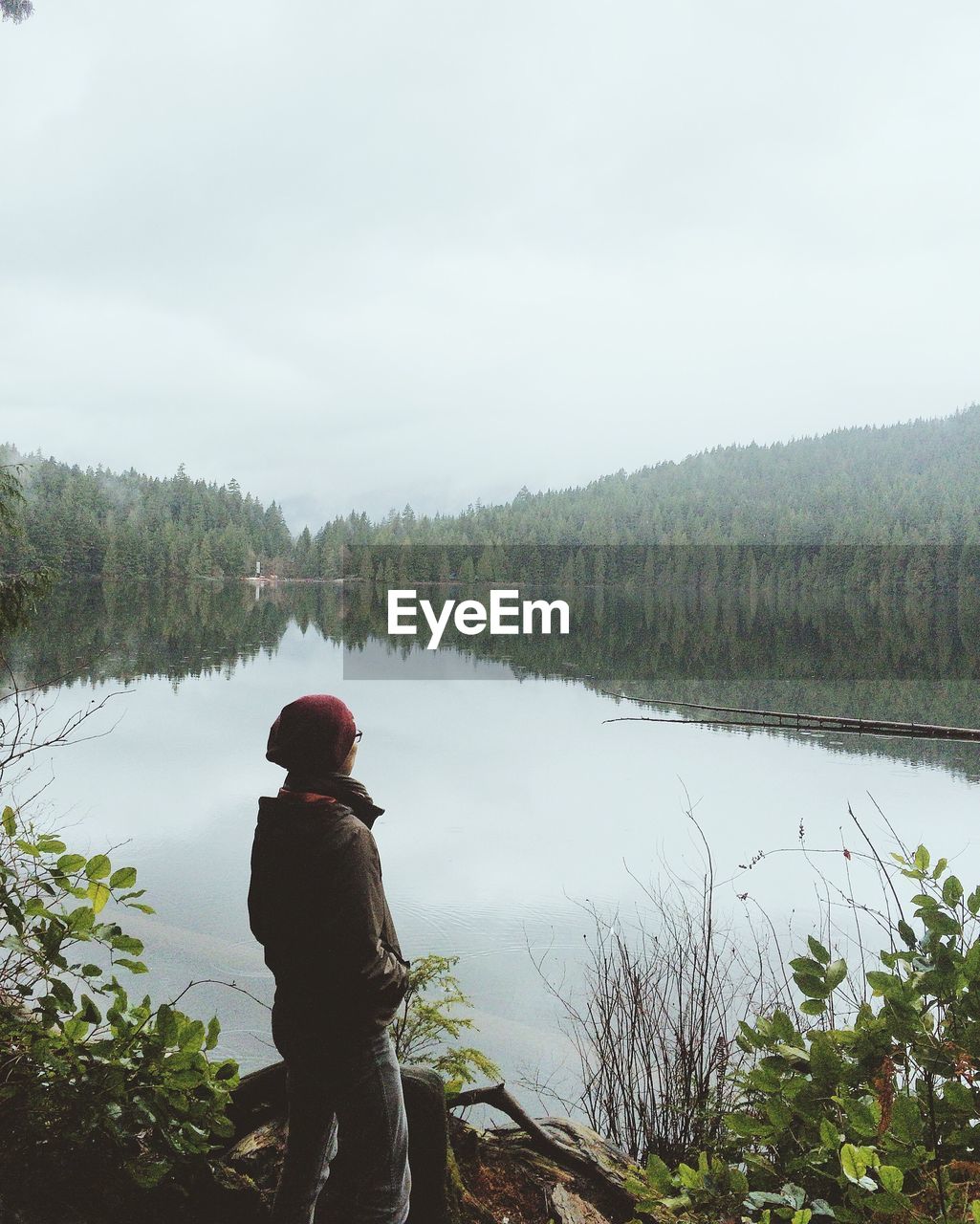 Rear view of woman looking at lake against sky