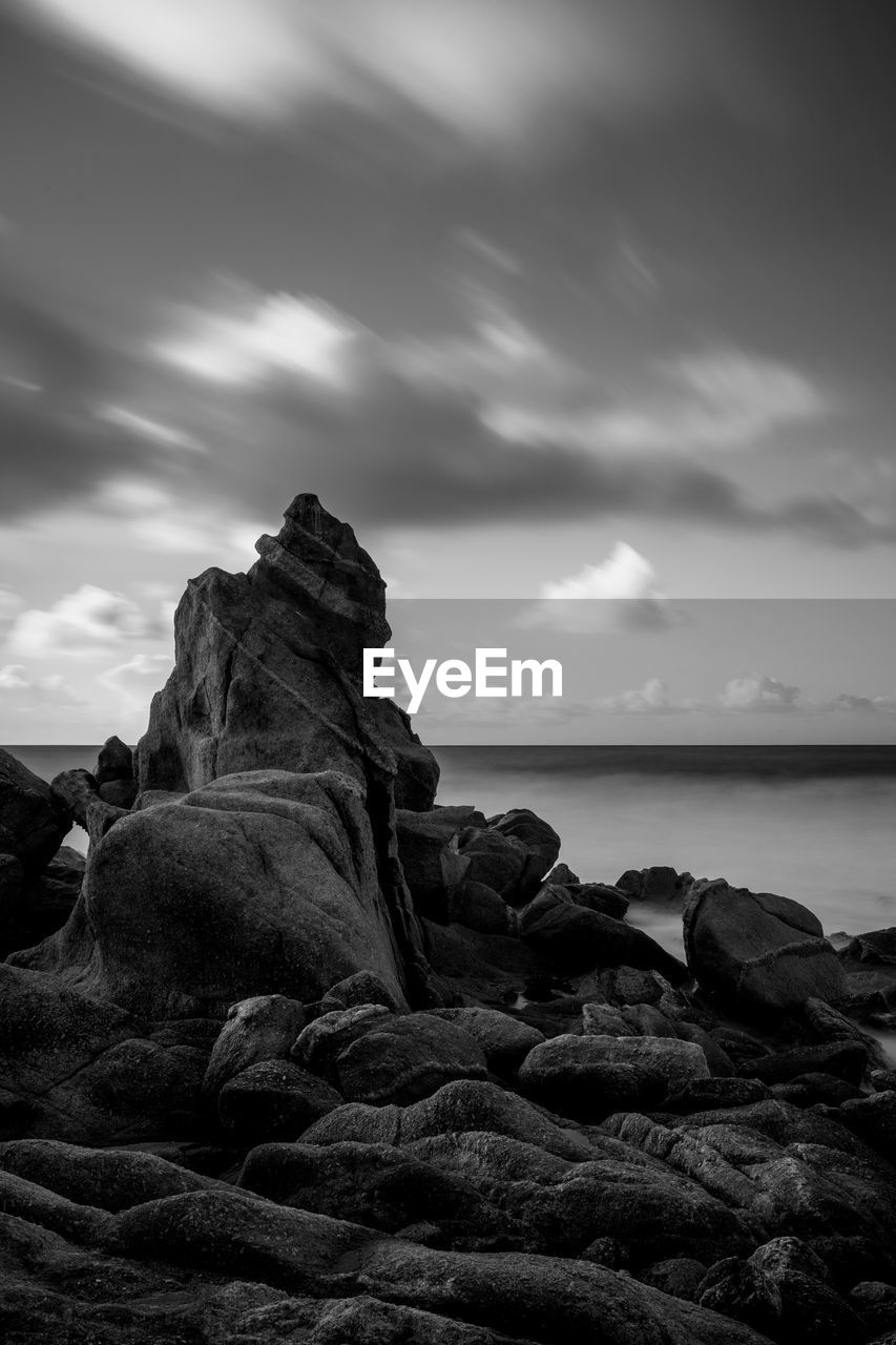 Scenic view of rocks by sea against sky