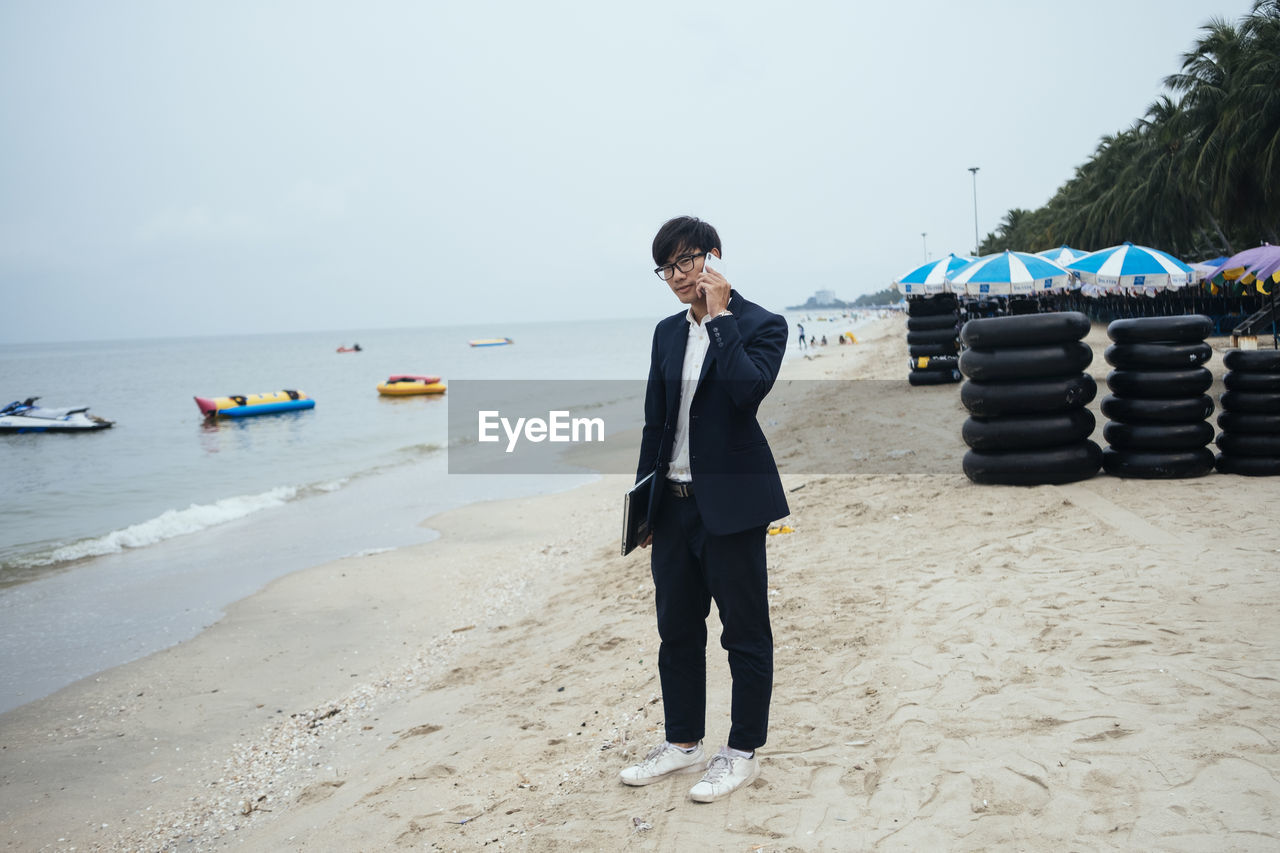 YOUNG MAN STANDING ON BEACH