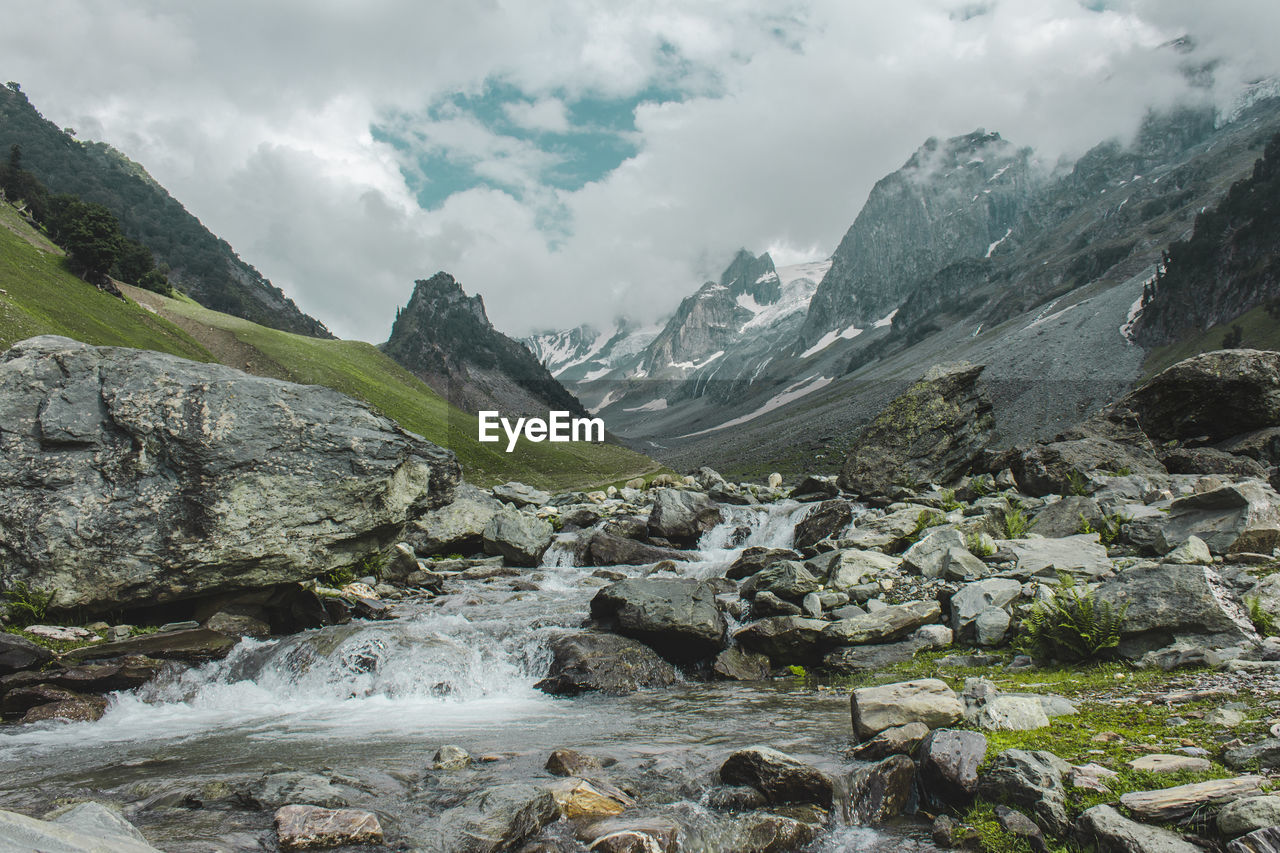 Scenic view of mountains and river against cloudy sky