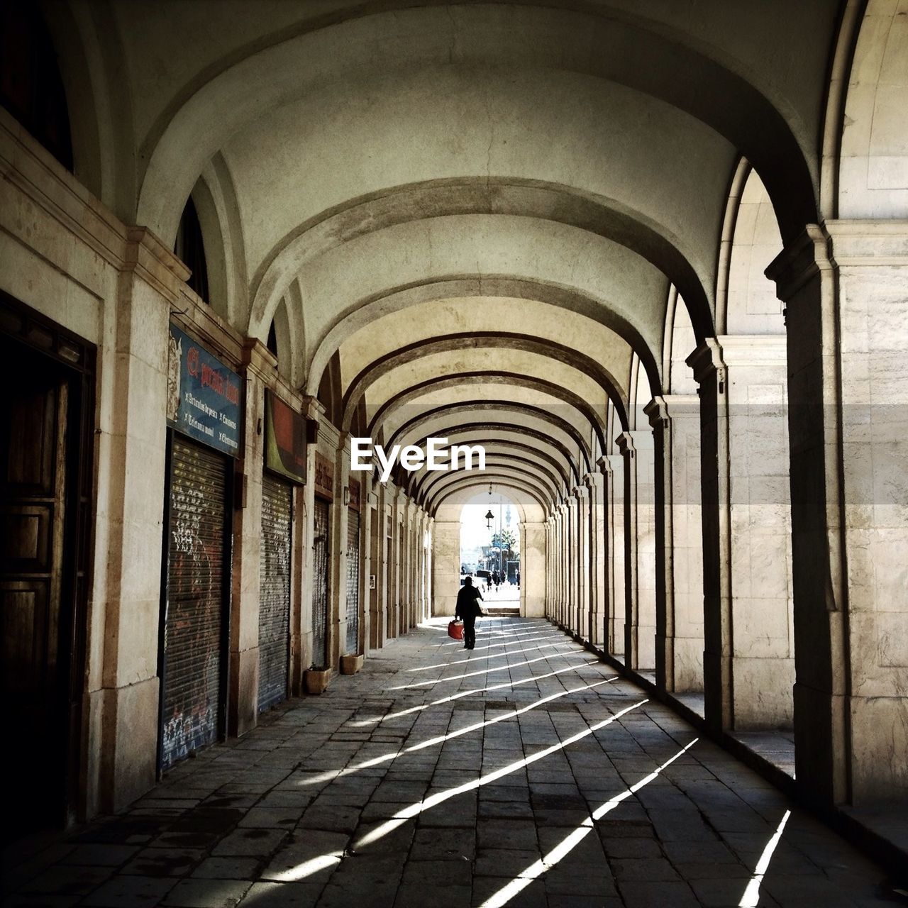 REAR VIEW OF MAN WALKING ON CORRIDOR OF BUILDING