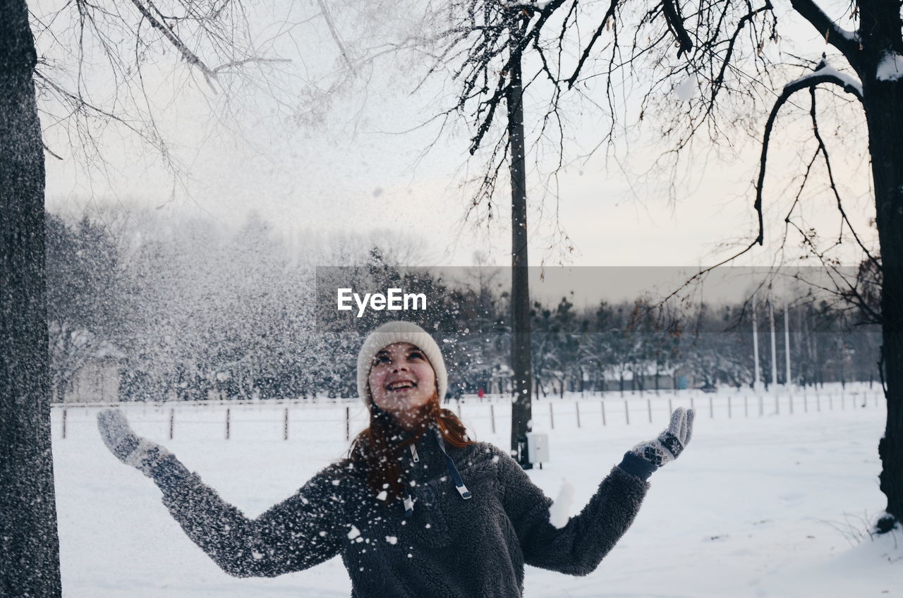 Woman playing with snow while standing outdoors