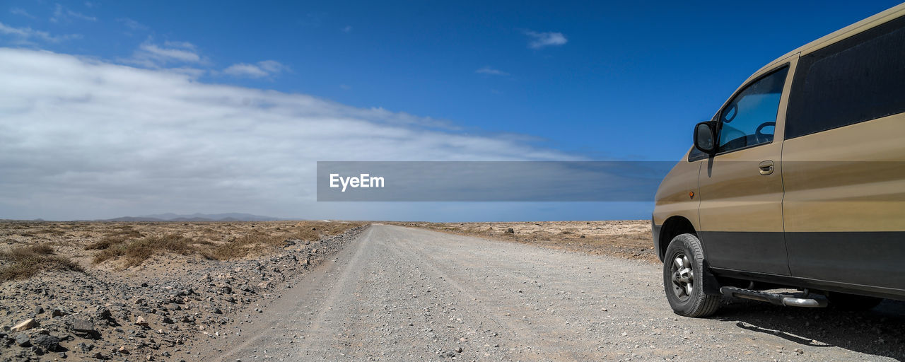 CAR ON ROAD BY LAND AGAINST SKY