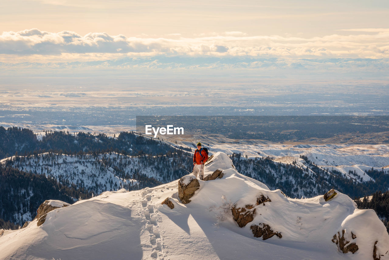 Man standing on snowcapped mountain against sky