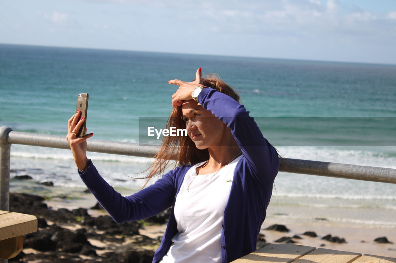 Woman taking selfie at beach on sunny day