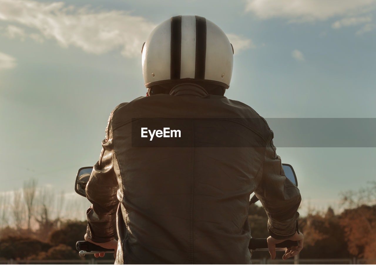 Rear view of man riding motorcycle against sky