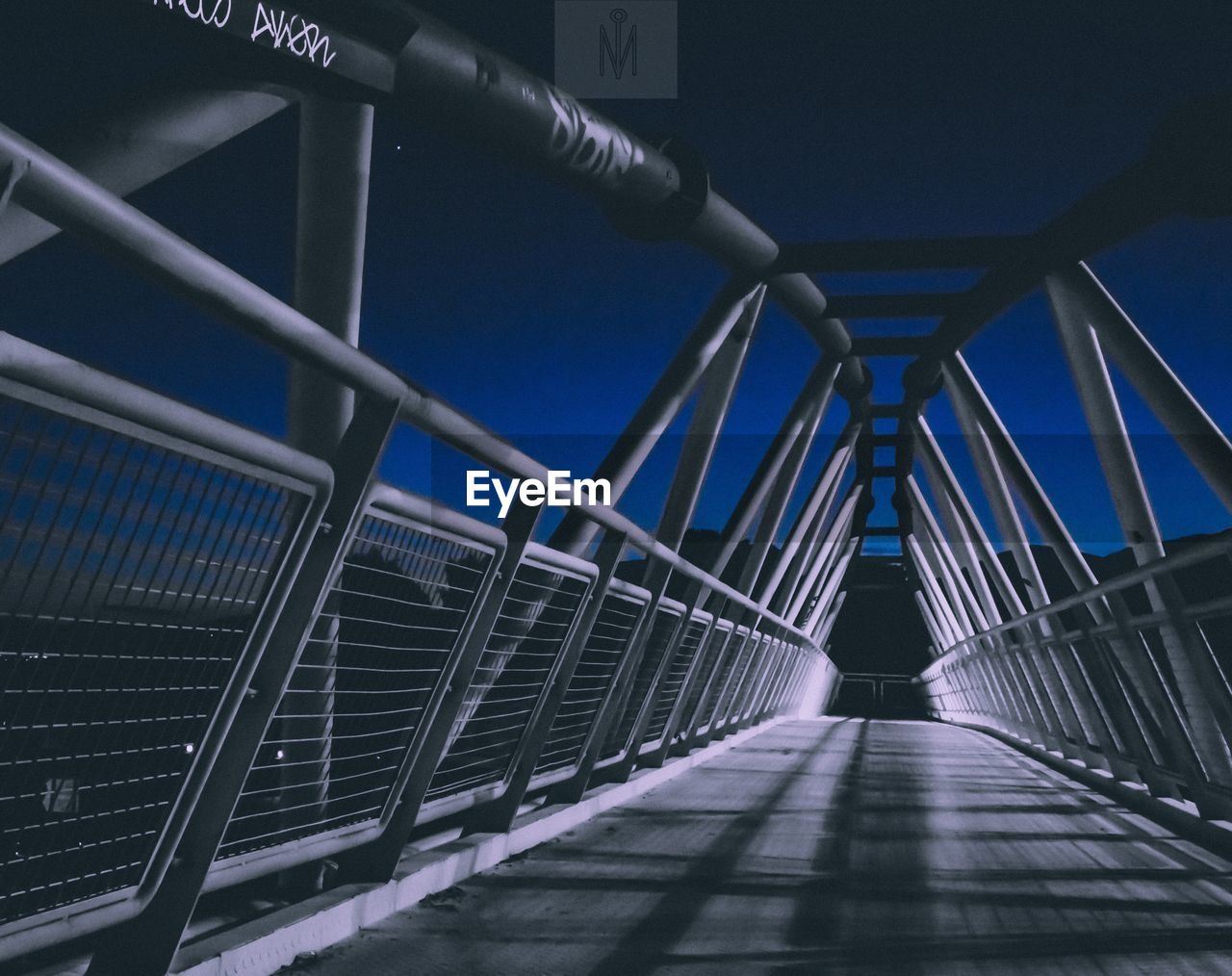 Low angle view of footbridge against clear blue sky at night