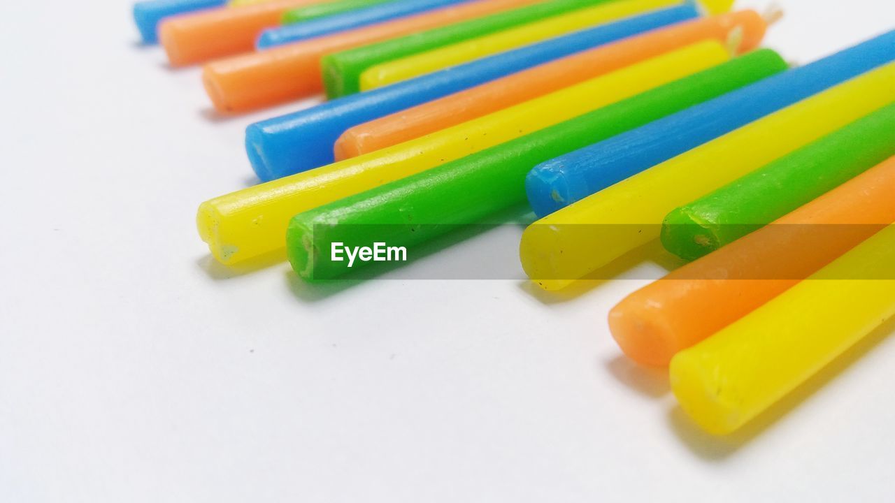 CLOSE-UP OF MULTI COLORED PENCILS ON WHITE BACKGROUND
