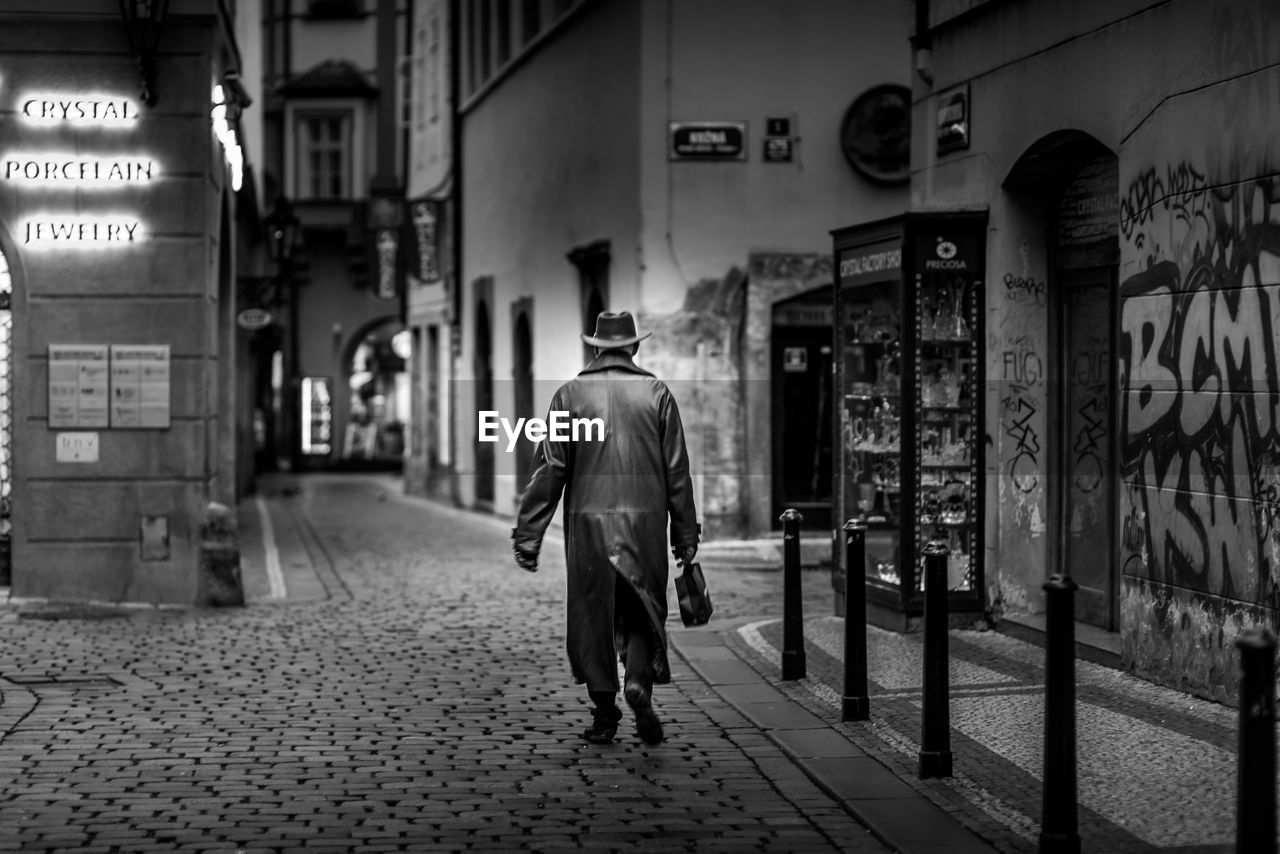 FULL LENGTH REAR VIEW OF MAN WALKING ON STREET