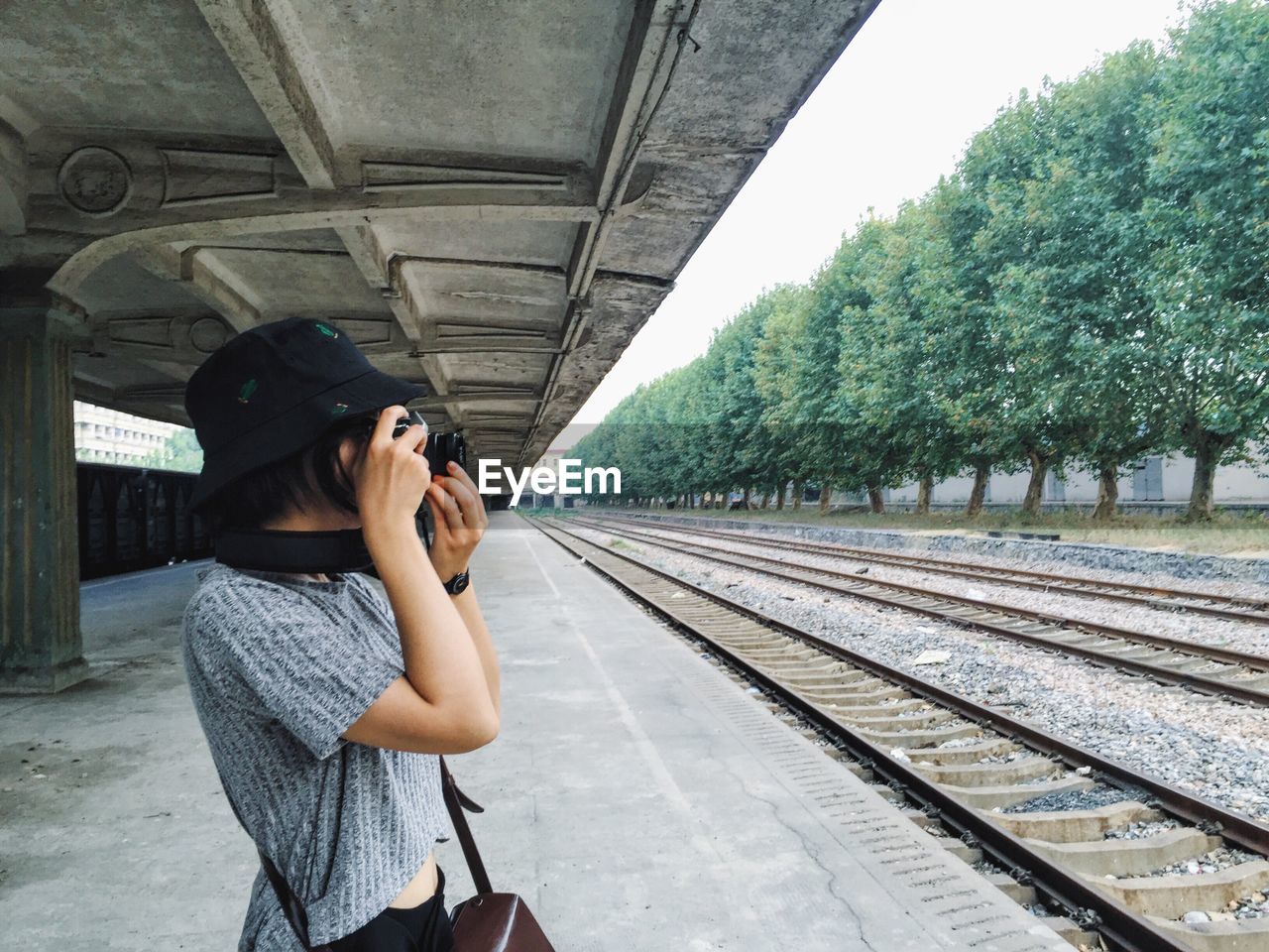 SIDE VIEW OF YOUNG WOMAN WALKING ON RAILROAD TRACK