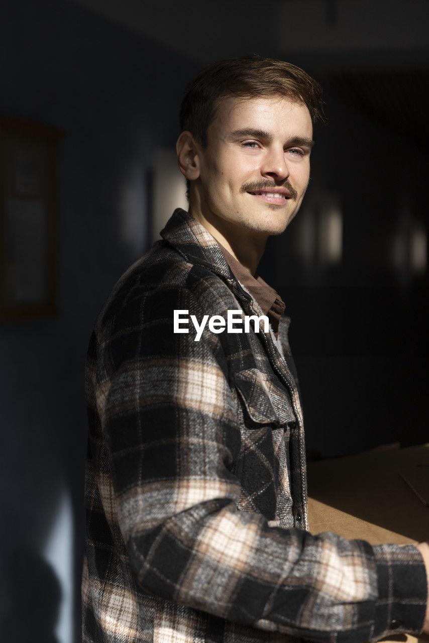 Side view of young man wearing flannel shirt at sunny day