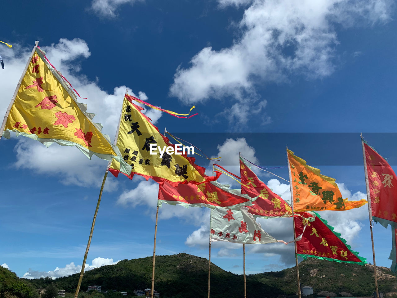 LOW ANGLE VIEW OF MULTI COLORED FLAGS HANGING AGAINST SKY