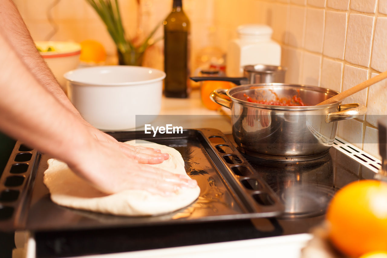 Cropped hands kneading dough in tray