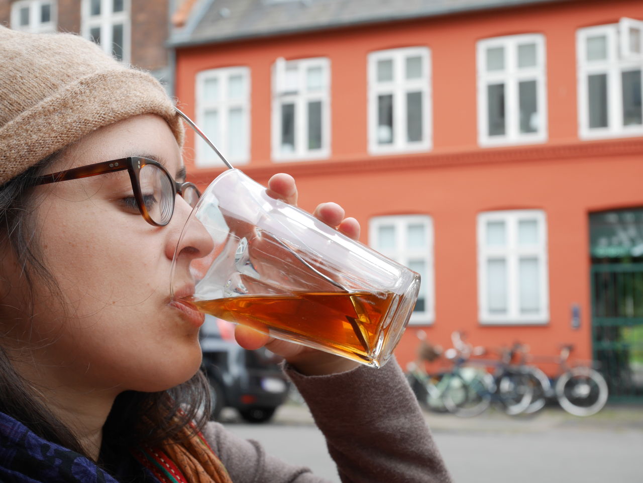 Side view close-up of woman drinking tea against building during winter