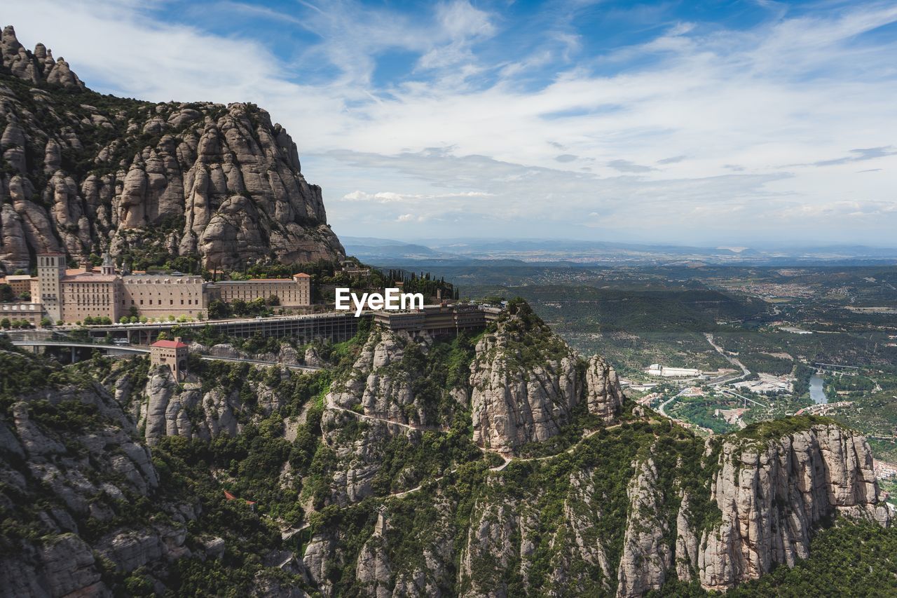 Scenic view of city by mountain against cloudy sky