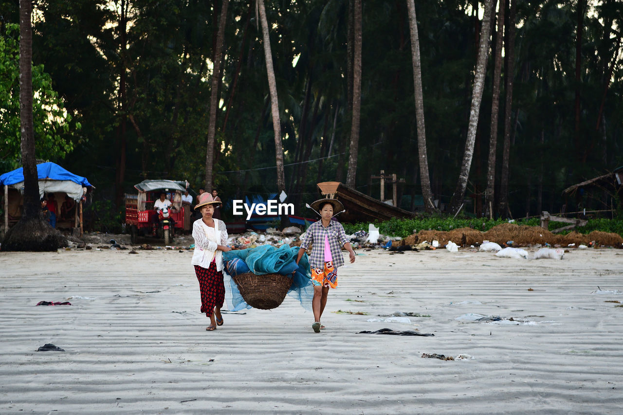 REAR VIEW OF PEOPLE WALKING ON LAND