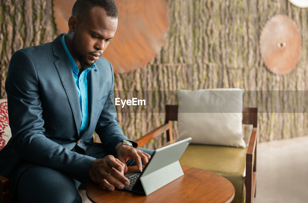 Midsection of businessman using laptop while sitting at office