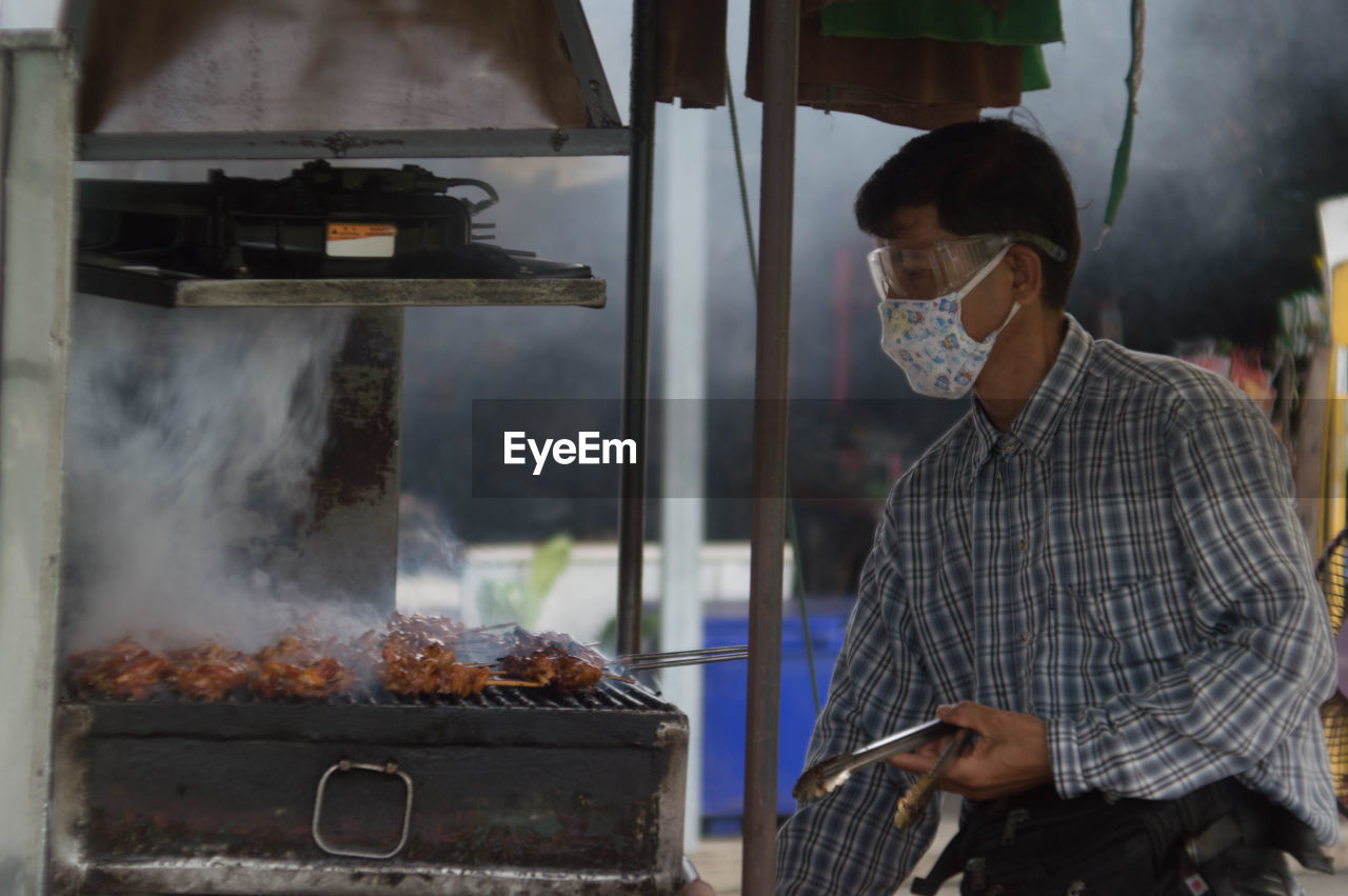 Man preparing meat on barbecue grill at market