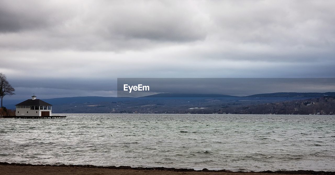 SCENIC VIEW OF SEA AGAINST BUILDINGS AND MOUNTAINS