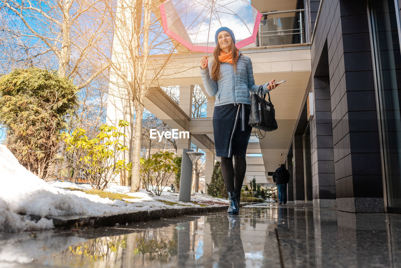 Low angle view of woman with umbrella walking on tiled floor