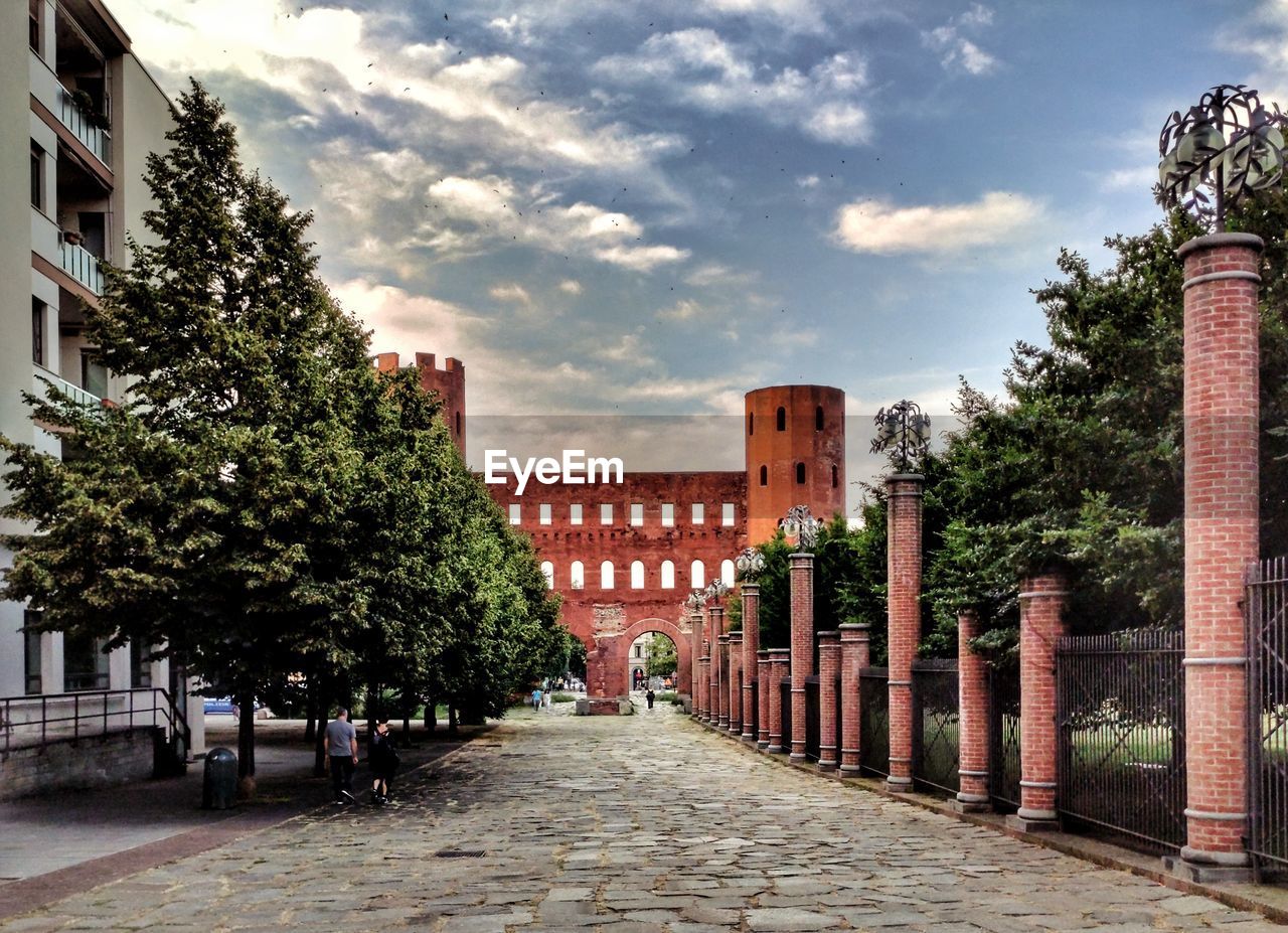 FOOTPATH AMIDST BUILDINGS AGAINST SKY