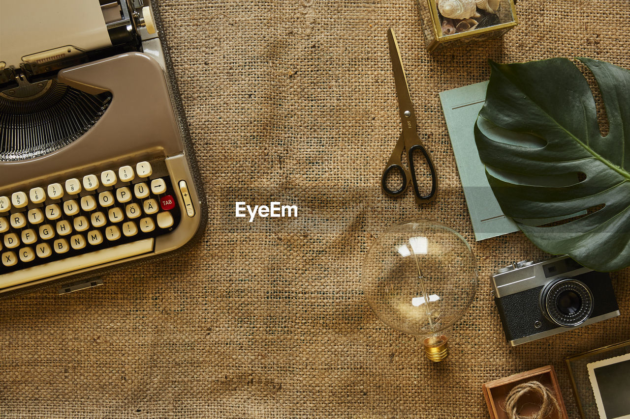 High angle view of light bulb with typewriter and camera on burlap