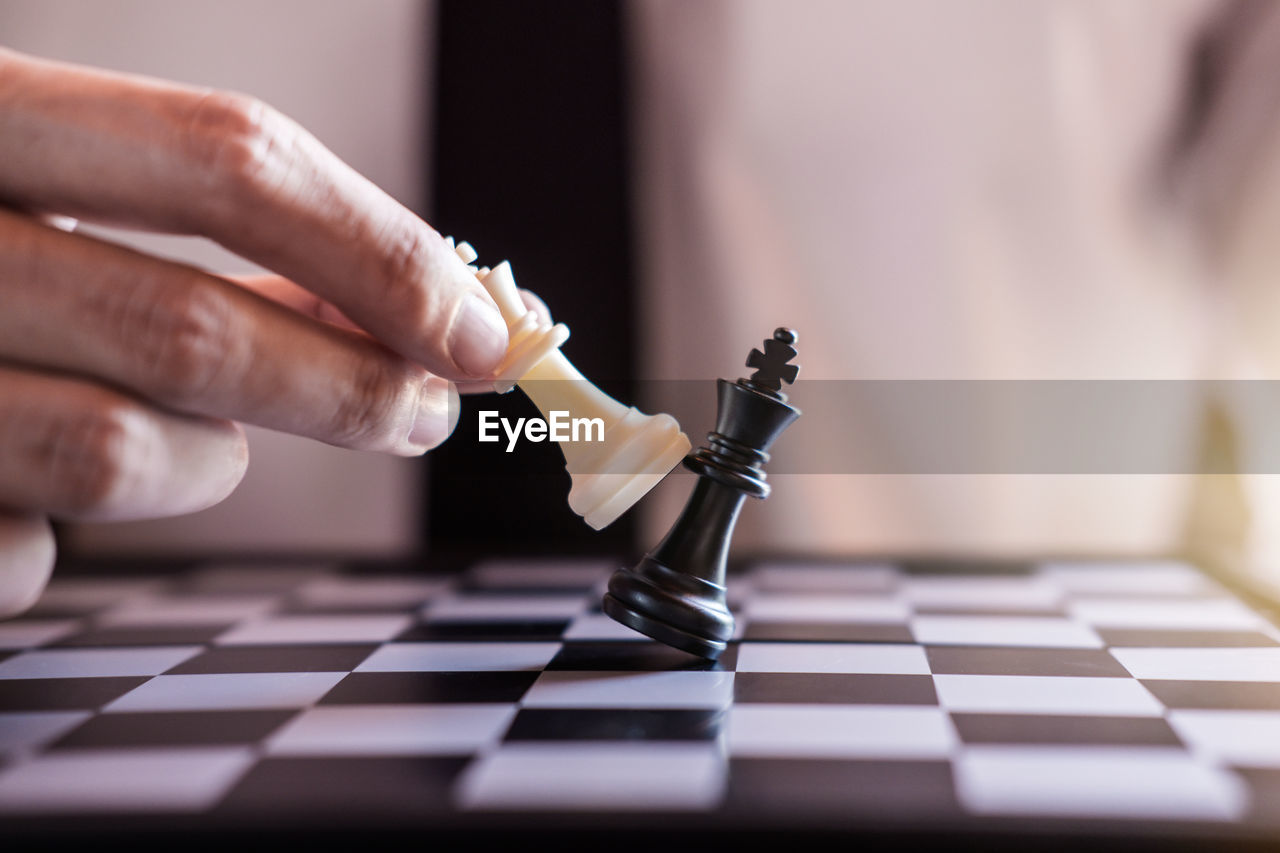 Midsection of businessman playing chess in office